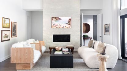 living room with white wall, a stone fireplace wall wiith art, boucle and sheepskin chairs
