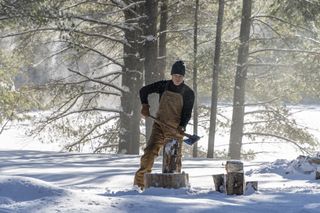 Michael C. Hall wearing dungarees, holding an axe standing in the snow as Jim Lindsey in Iron Lake, NY