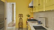 A small kitchen with yellow walls and cabinets