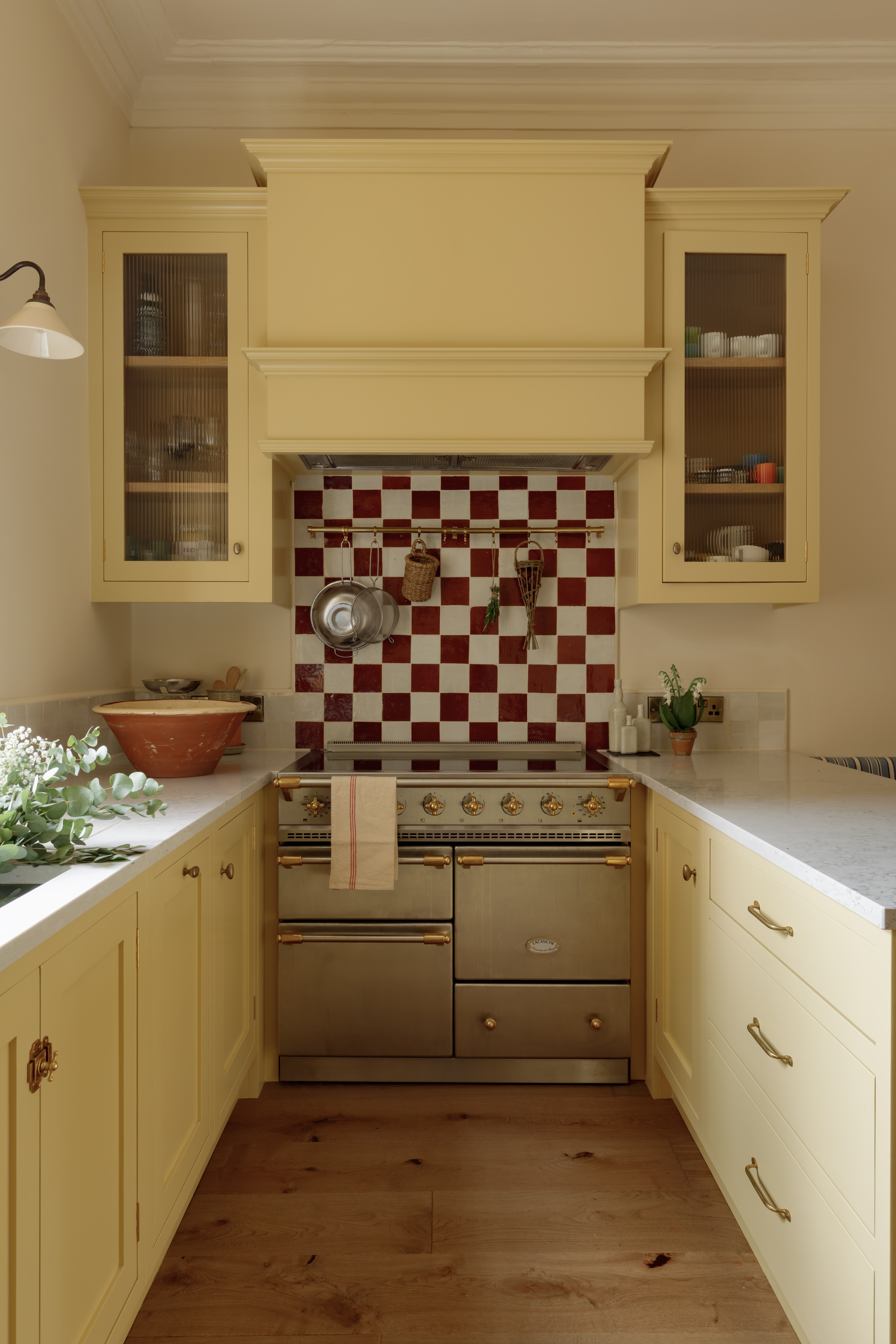narrow kitchen with butter yellow cabinets, a range cooker, and a checkerboard tile backsplash