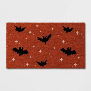 Halloween Bats Coir Doormat Orange against a gray background.