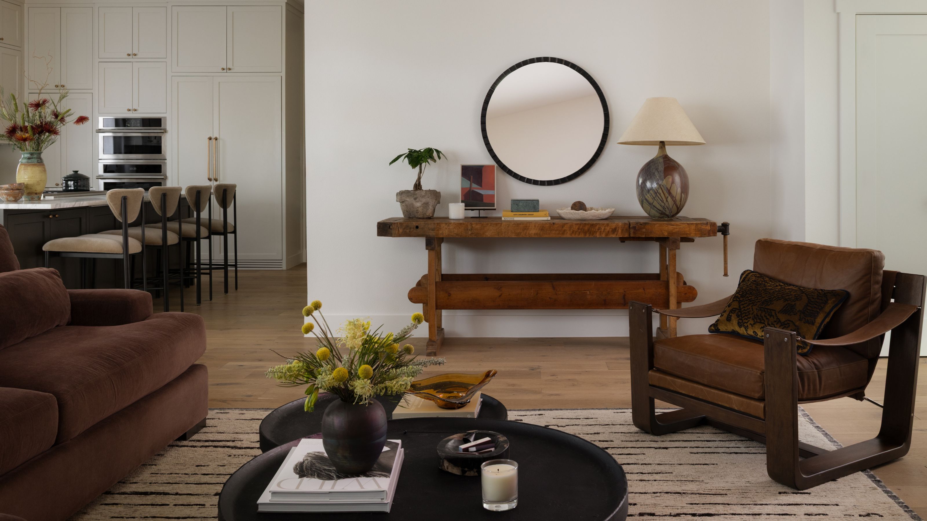 a neutral family room with views into the kitchen. vintage rustic and century furniture is styled for a casual sitting room area