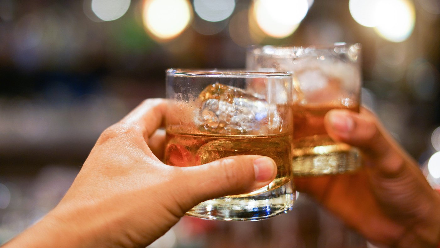 Two people clinking glasses of bourbon