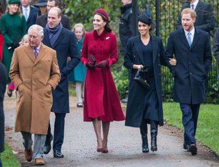 King Charles, Prince William, Kate Middleton, Meghan Markle wearing coats and hats heading to church on a wet path