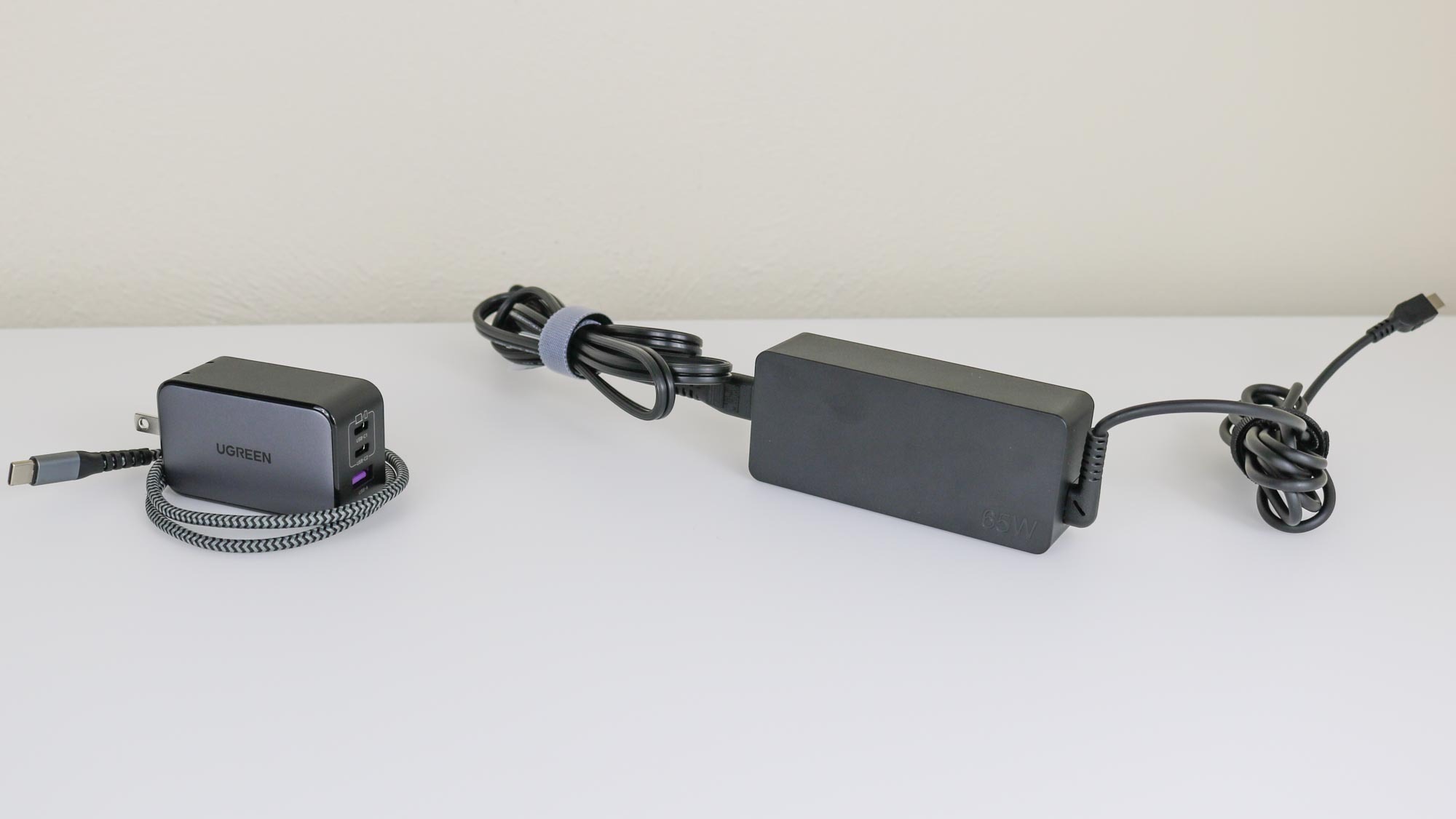 A typical laptop charger compared in size to the UGREEN Nexode 65W Charger