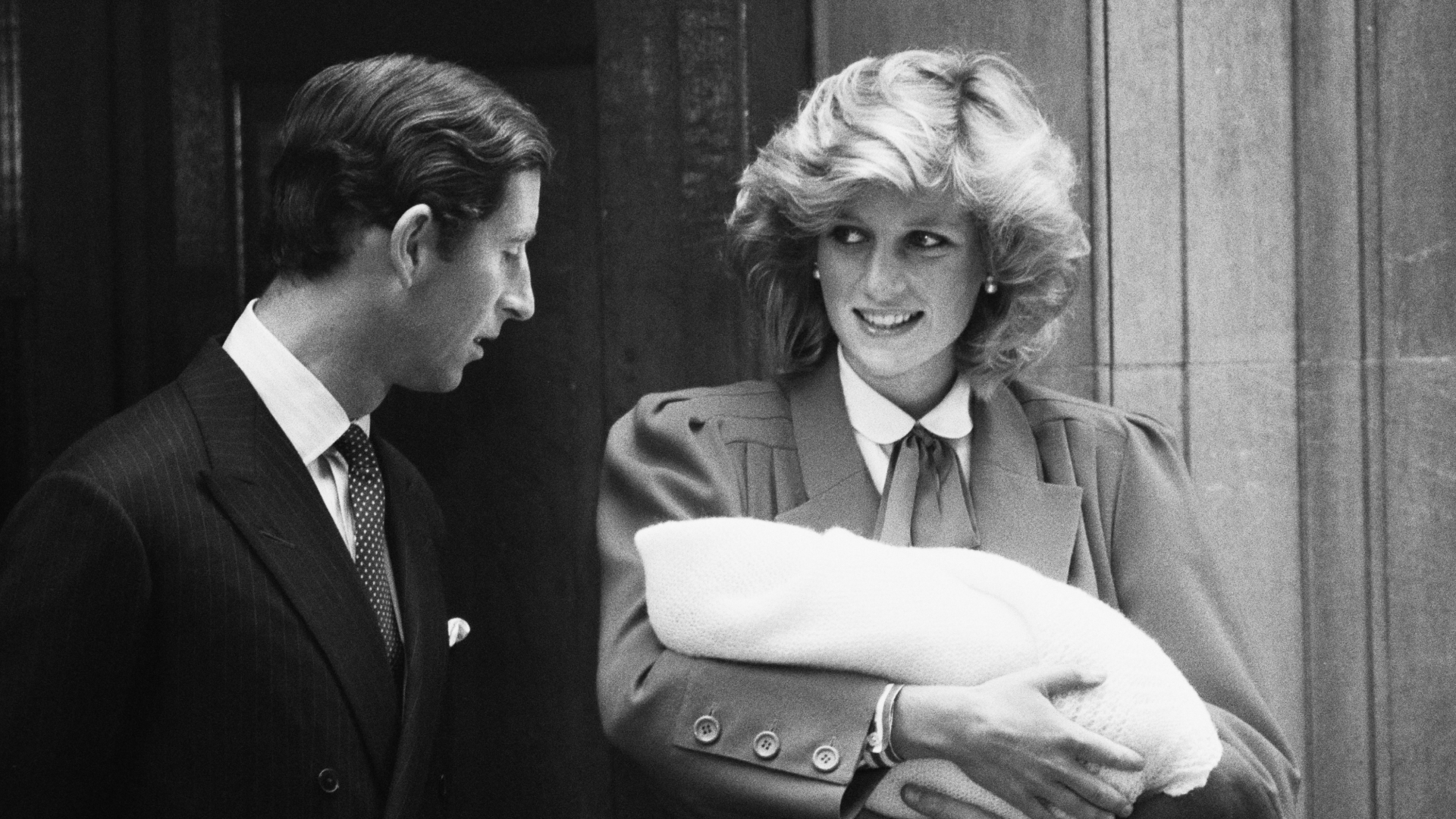 Prince Harry and Princess Diana standing on hospital steps holding Prince Harry as a newborn