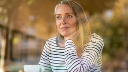 woman looking contemplative drinking from a mug