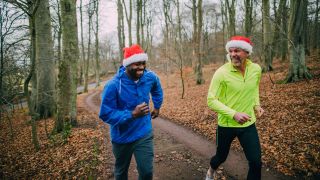 Two runners on forest trail wearing Santa hats
