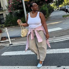 Aniyah wears white tank, khaki barrel pants, long-sleeve tied around her vase