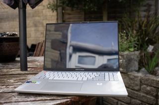 A silver ASUS Vivobook Pro 16X OLED laptop sitting on a wooden table