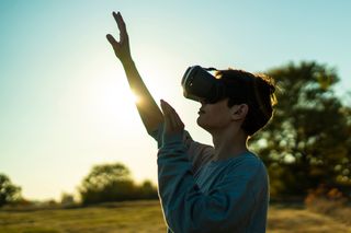 a woman using a VR headset outside in nature