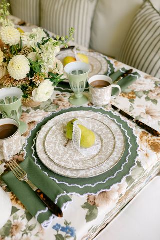 fall table decor with green linen placemat and napkins, pear as placecard, and fresh foliage