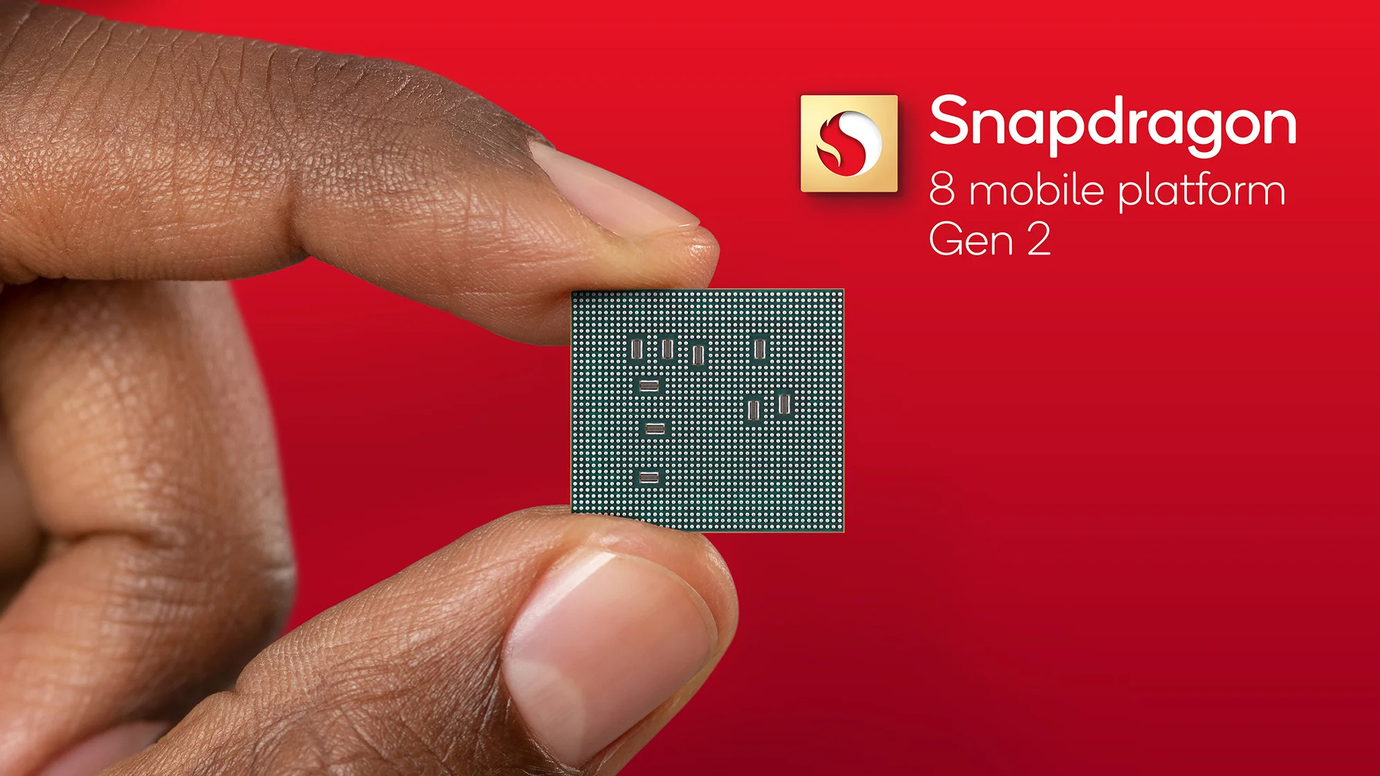 Imagen de dedos sosteniendo el chip Qualcomm Snapdragon 8 Gen 2 sobre un fondo rojo