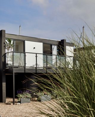 exterior of 1960s container style coastal home with shingle and coastal grasses