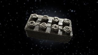 A roughly sculpted grey lego brick floats in space.