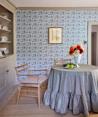 blue pheasant wallpaper in kitchen with round table covered in blue striped tablecloth with floounced skirt