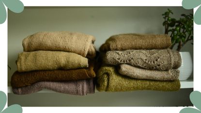 Eight green and brown jumpers folded on a shelf next to a plant