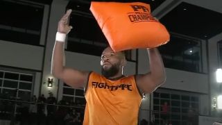 Leandro Apollo raises an orange pillow over his head following the championship fight