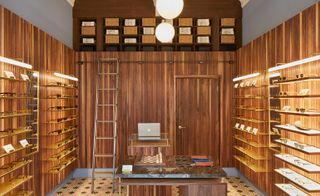Interior of menswear shop. Wooden panelled walls with shelves of sunglasses