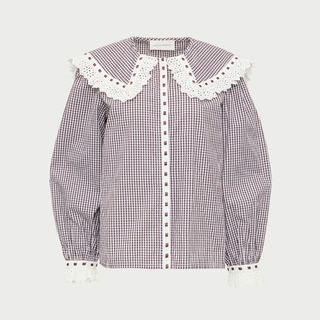 A cutout of a check blouse with an oversized collar set against a light grey background