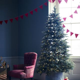 room with blue wall and pink chair and christmas tree