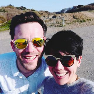 Clio and her husband wearing sunglasses and smiling