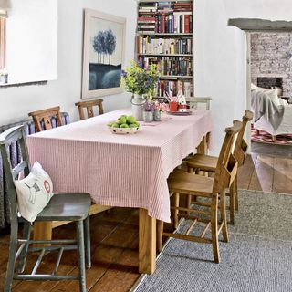 A white rustic family dining area with a table and built in bookcase