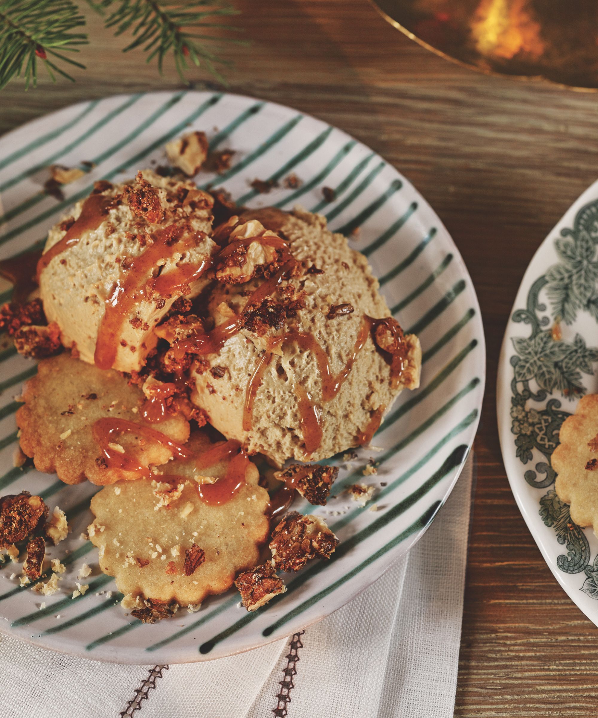 Butterscotch mousse with sauce and biscuits on a green and white striped plate