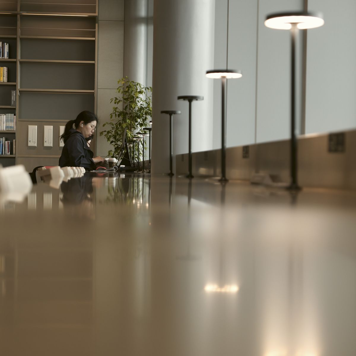 Sample image taken with the Panasonic Lumix L10; person studying in a library, they are reflected in the shiny table