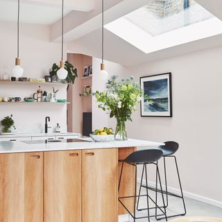 A modern kitchen with light wood kitchen island, pendant light fixtures and skylight