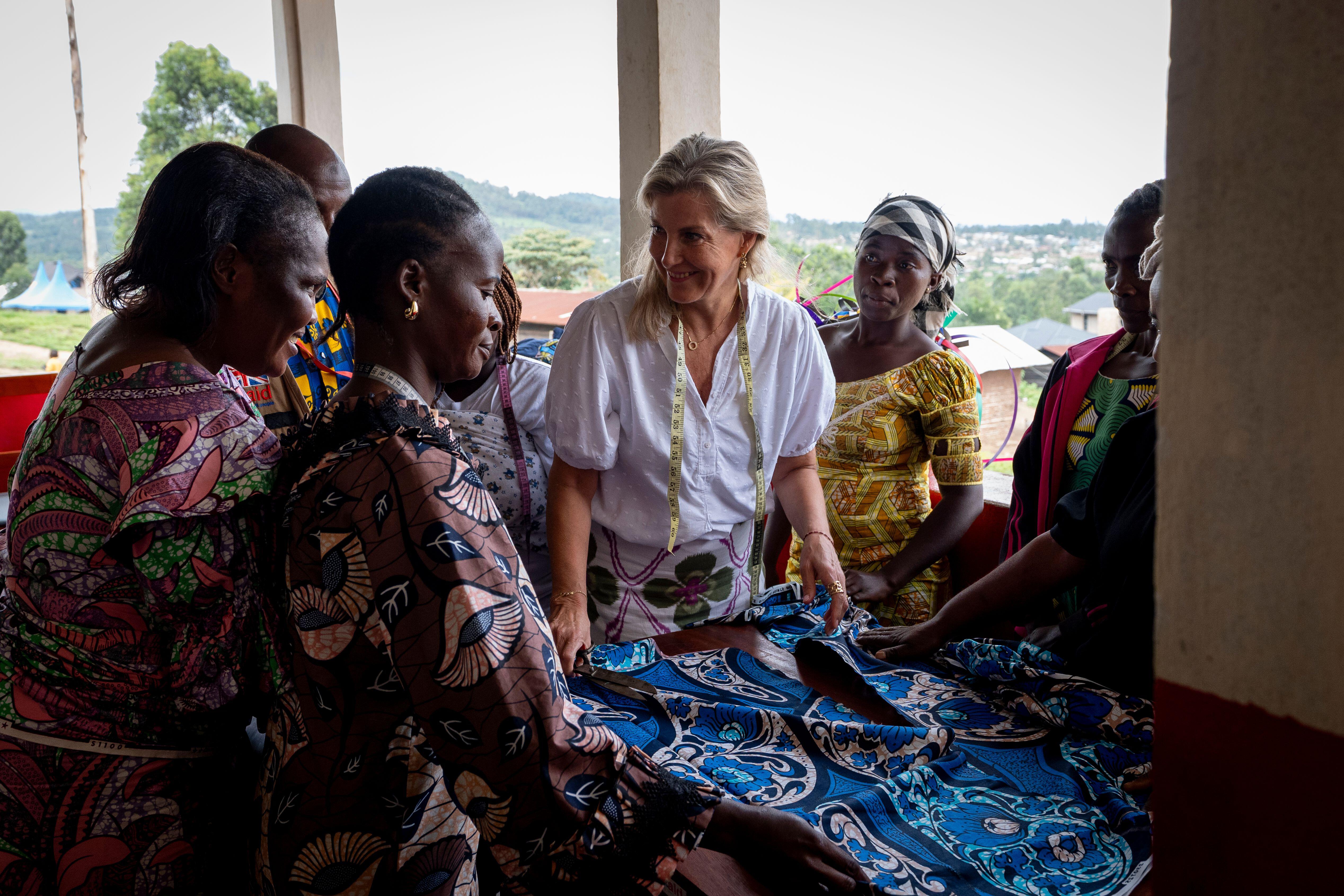 Duchess Sophie looking at a piece of blue fabric with a group of women in Congo wearing traditional garments