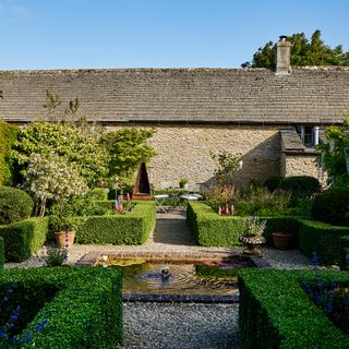 cottage gravel garden with box hedged flower beds, pond and fountain