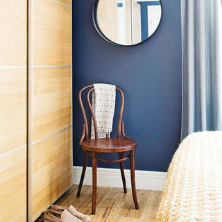 navy blue bedroom with sliding wardrobe doors and wooden chair