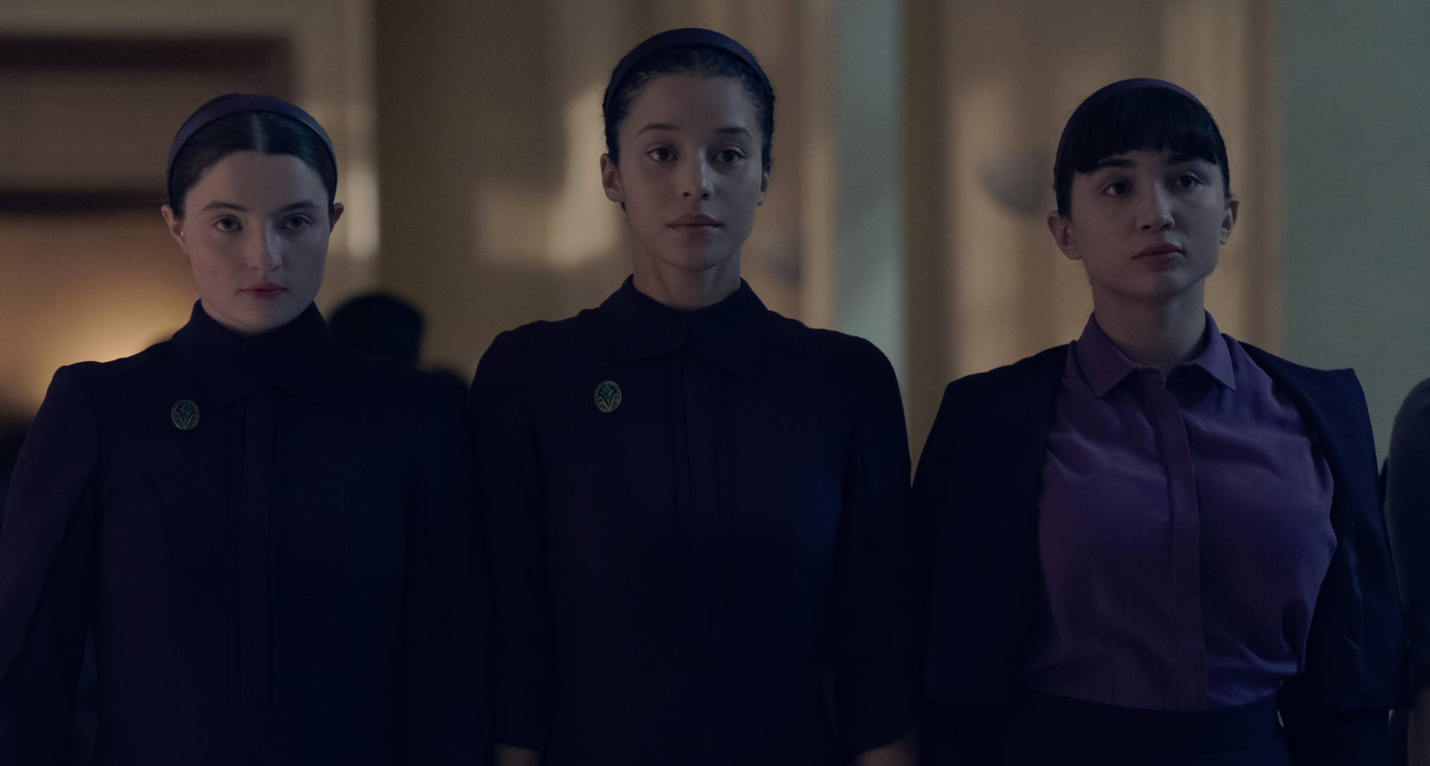 three girls including lucy halliday chase infiniti and rowan blanchard wear dark purple dresses walking down a hall in the testaments season 1 finale
