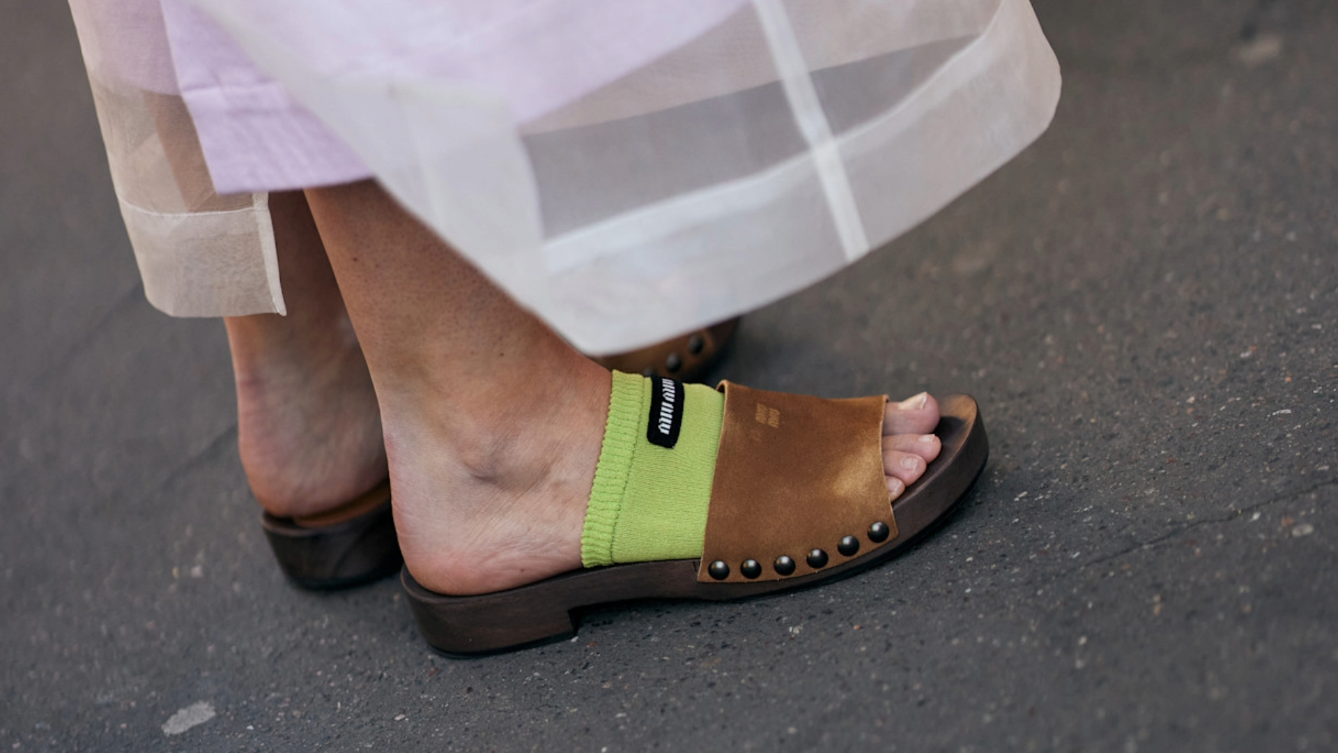 woman wearing brown suede sandals and a green foot band