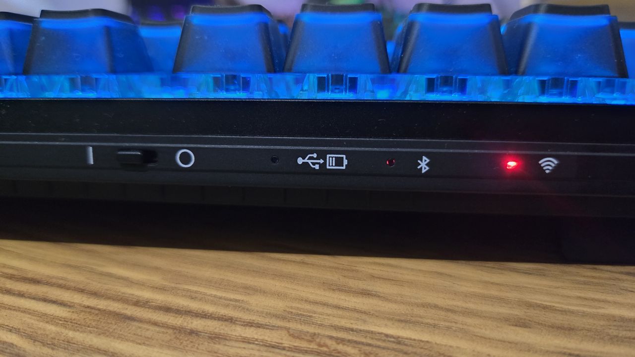 The Cherry MX 8.2 Wireless Xaga back edge, showing the red lights indicating various device connections. The RGB lights are on, and bathe the visible keycaps in blue light.