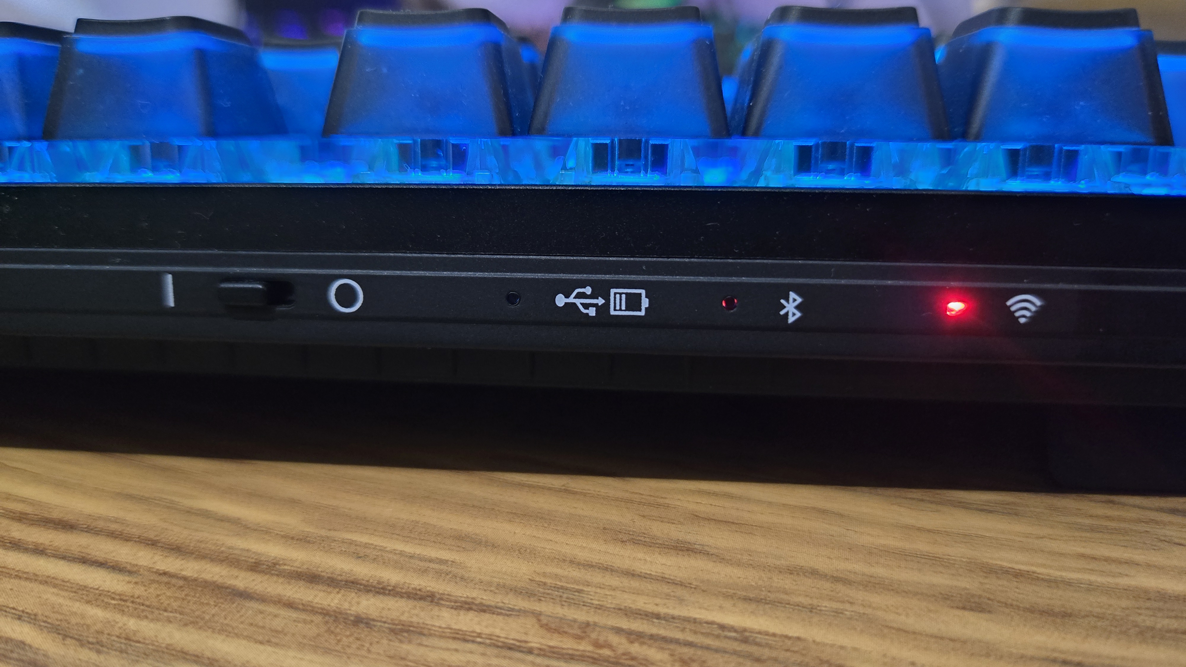 The Cherry MX 8.2 Wireless Xaga back edge, showing the red lights indicating various device connections. The RGB lights are on, and bathe the visible keycaps in blue light.