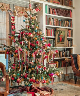 a vintage Christmas tree with colorful ornaments and a vintage artwork in a gold frame hung from the bookshelves