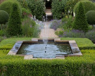 formal pond with a small fountain planted in a box parterre