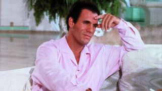 Robert Davi sits thinking on a couch in Licence To Kill.