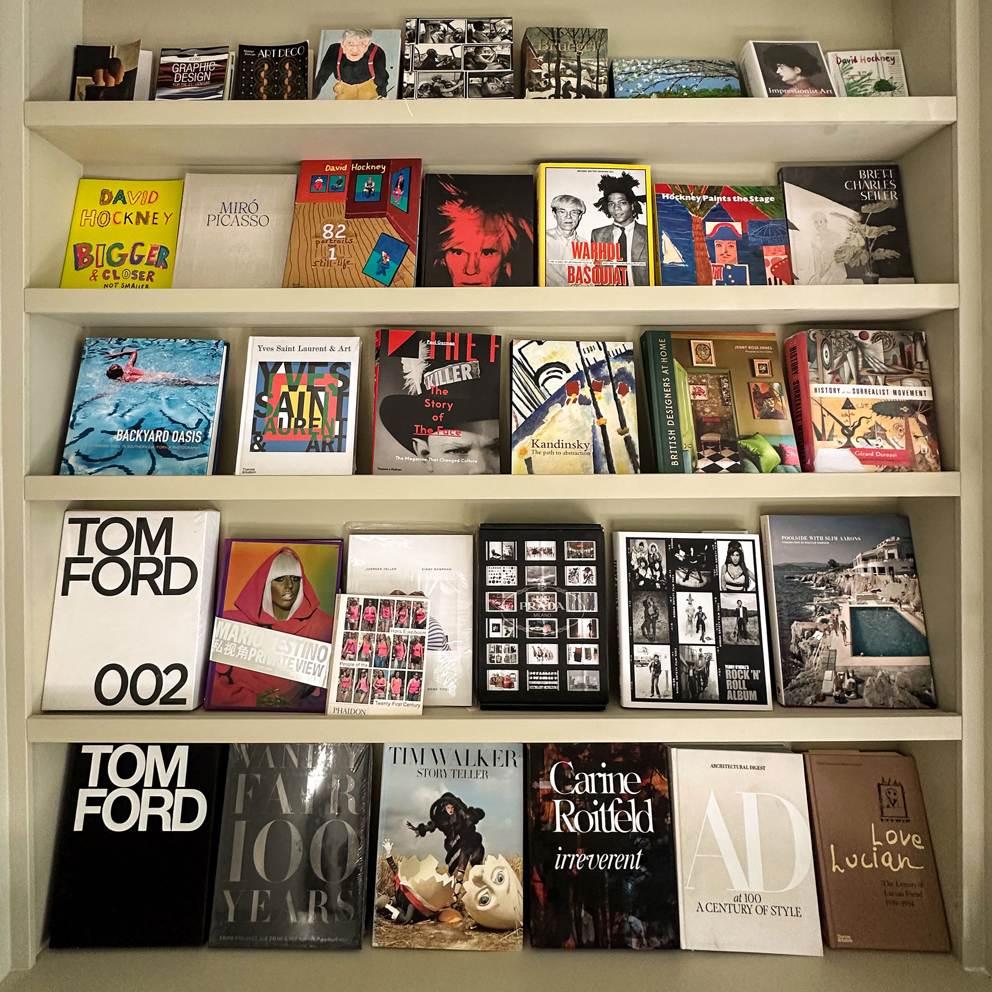 Pale green built-in bookshelves with coffee table books on display