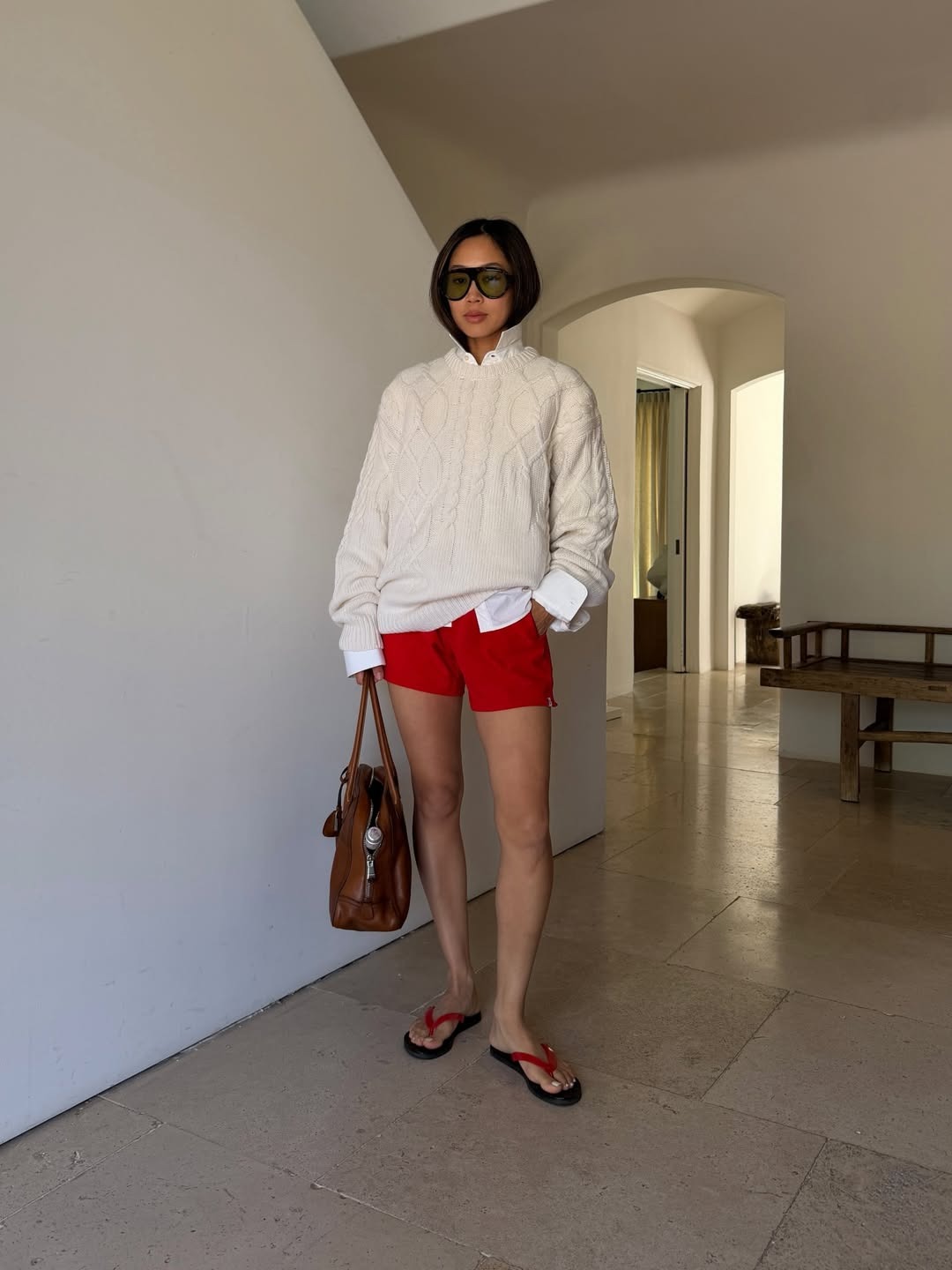 Woman in cable knit sweater and red shorts.