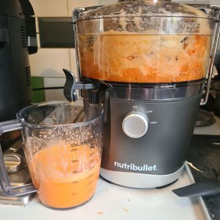Nutribullet juicer being used for carrots on a kitchen counter