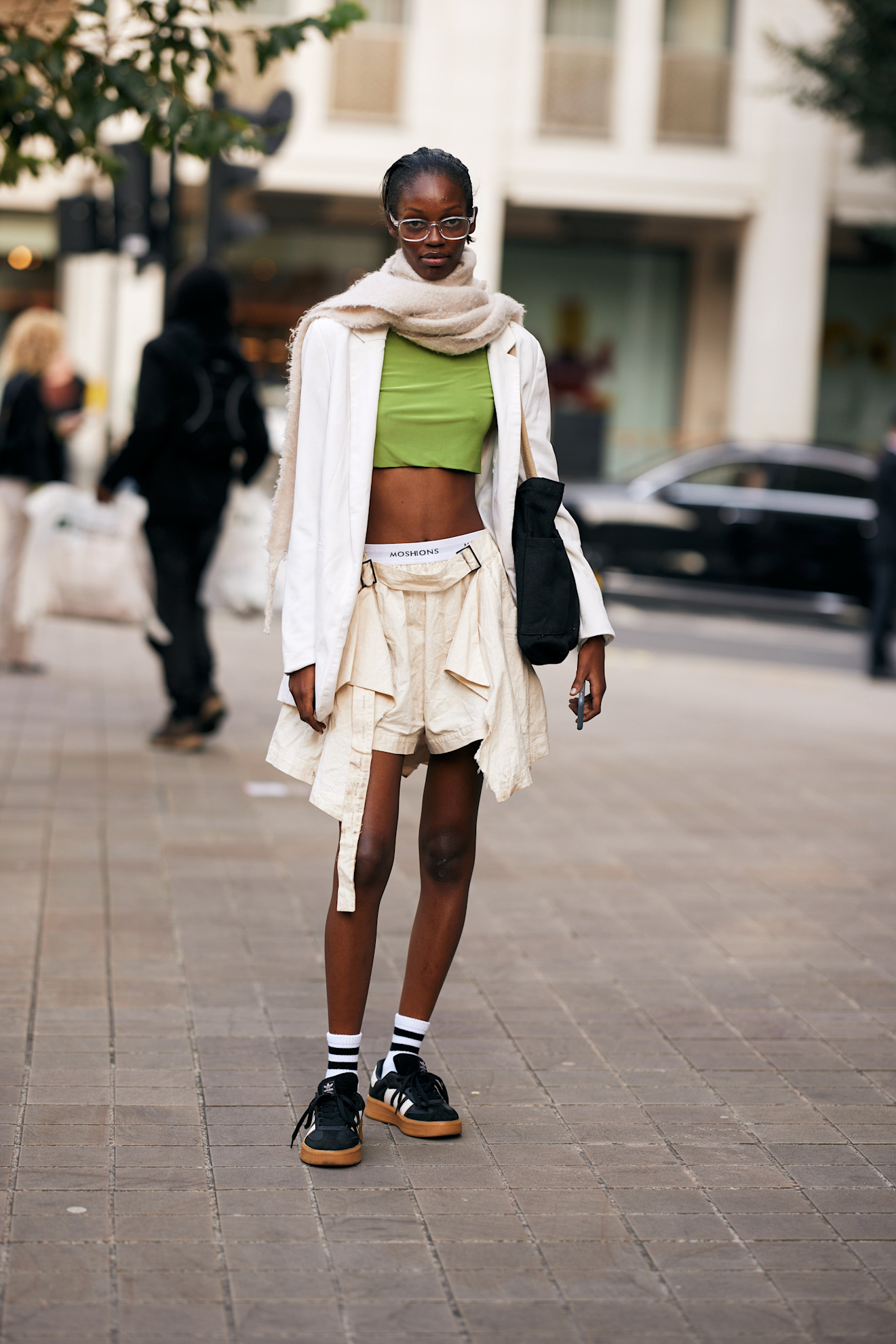 woman wearing adidas sneaker and shorts and a green top in London