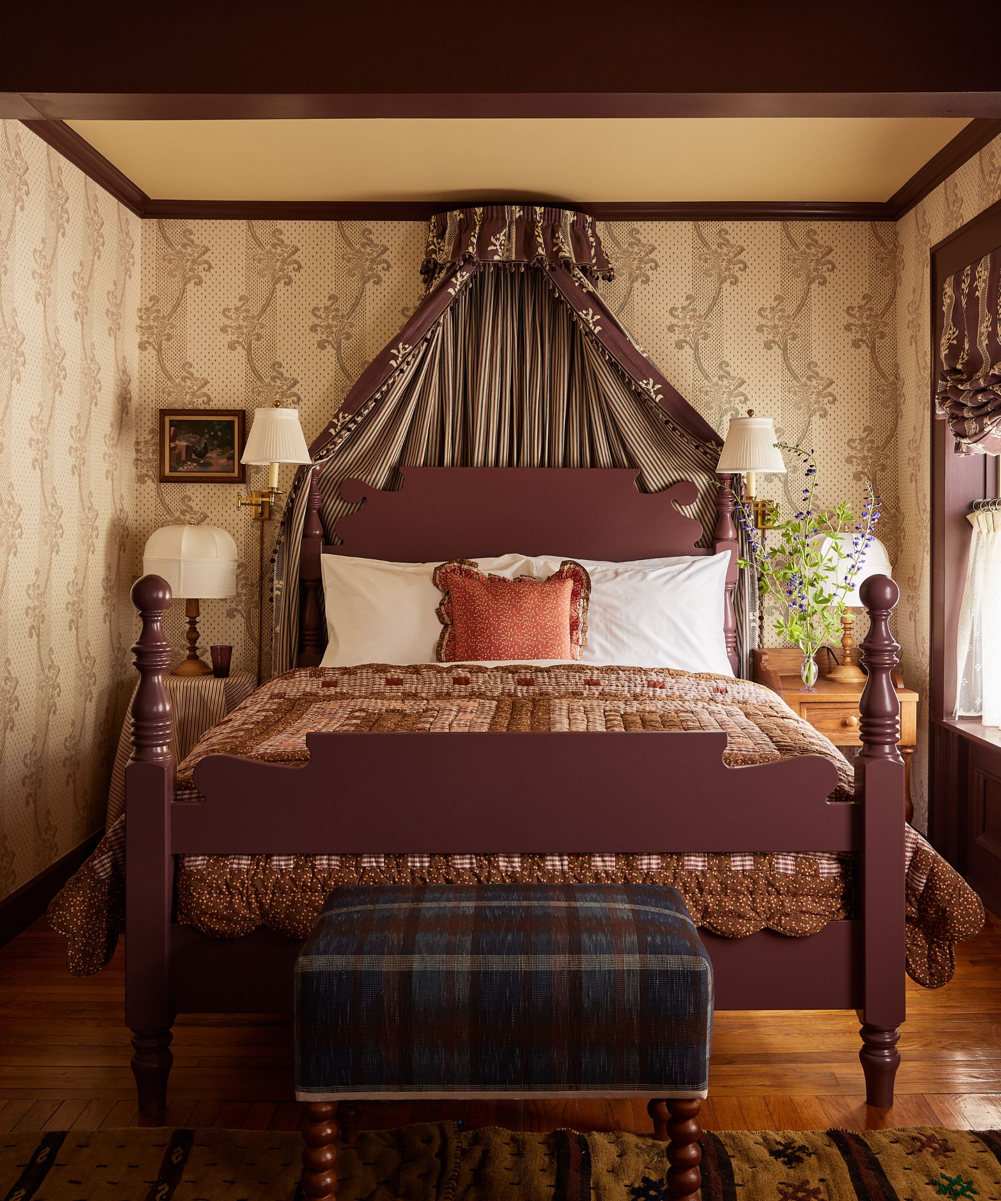 The Six Bells bedroom with floral wallpaper, patchwork quilt and bed coronet. Photography by Kate S. Jordan