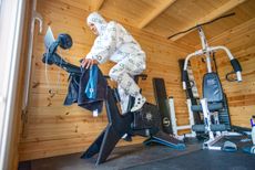 Rider in white heat overalls on a smart-bike in a wooden shed