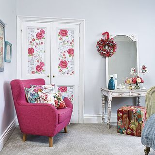 white bedroom with pink armchair and carpet floor