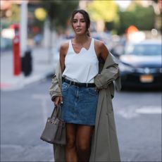 woman in mini skirt outfit of denim mini skirt tank top and trench coat
