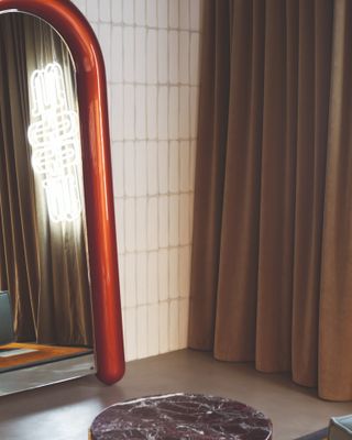 White tiles wall with brown curtain and a red metal trimmed full length mirror