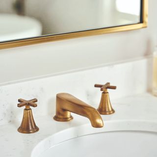 White bathroom sink with brushed brass tap and mirror